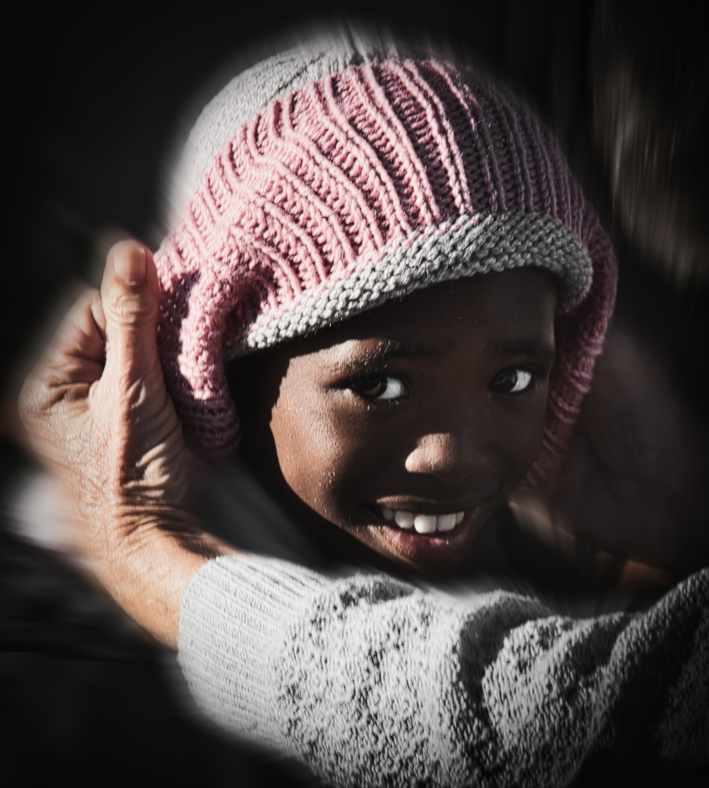 Child smiling in a pink beanie